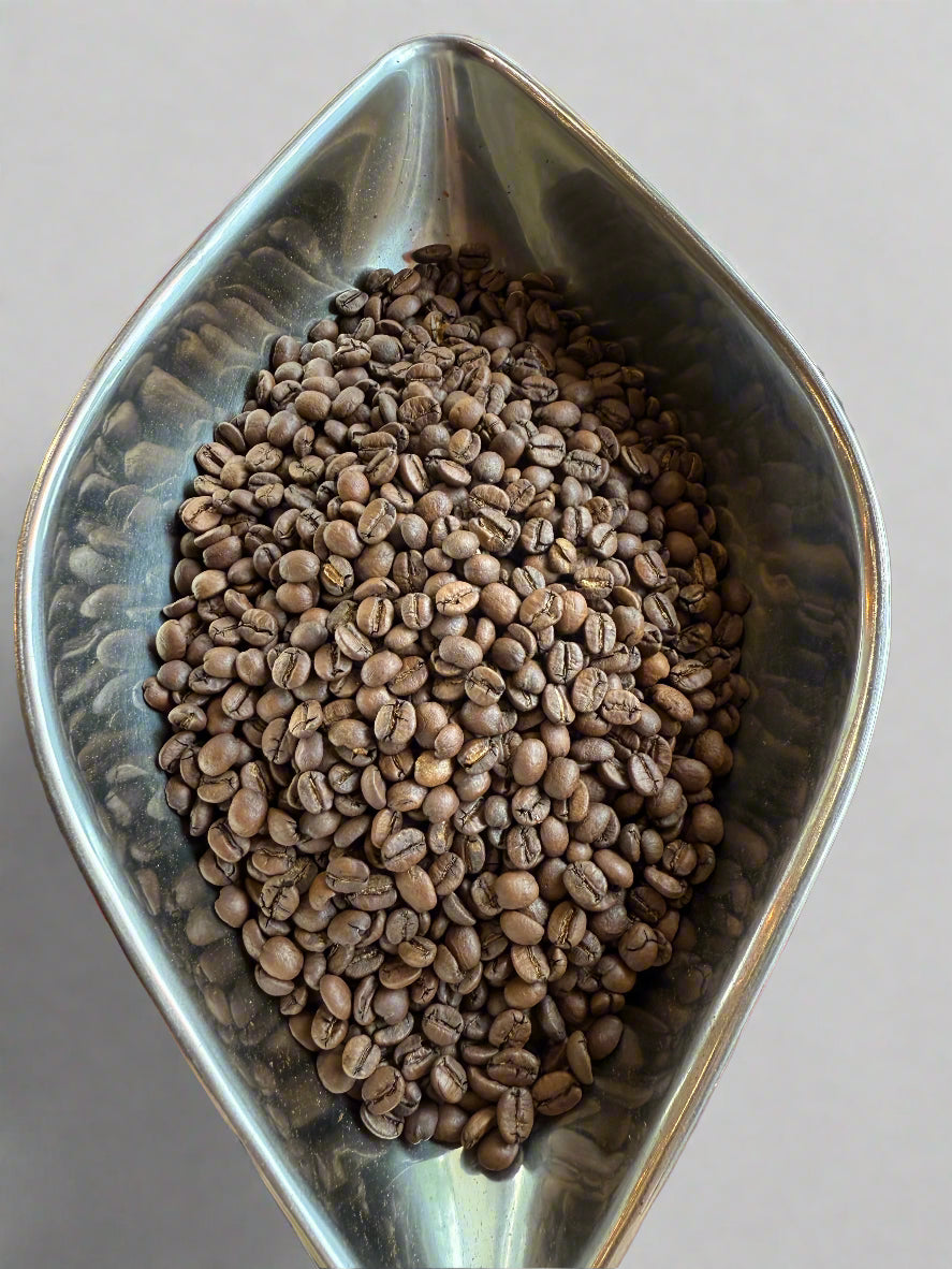 Metal bowl filled with coffee beans on a blurred background