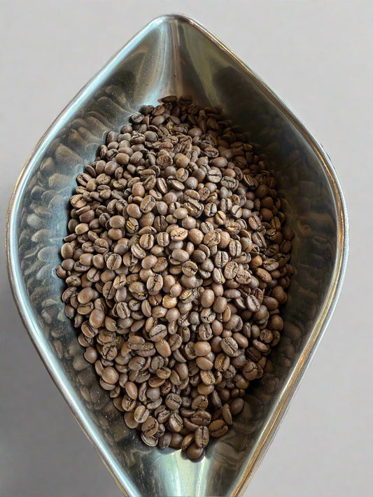 Metal bowl filled with coffee beans on a blurred background